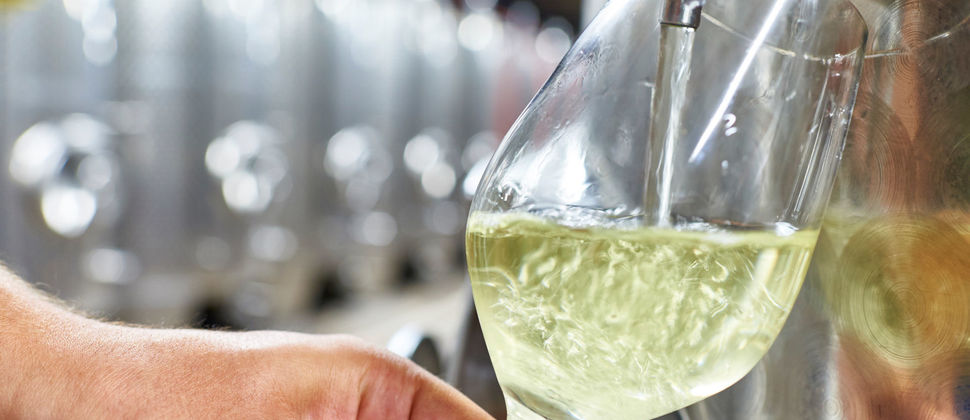 Im Weinkeller wird Wein in ein Glas abgefüllt.